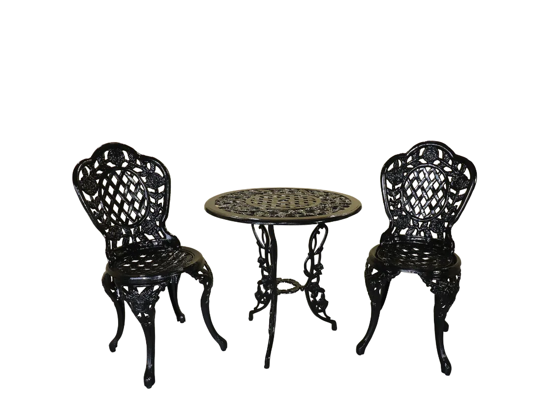 Black cast iron rose-pattern bistro set with two lattice-back chairs and a matching round table on a garden terrace.